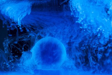 Mavi boyalı cam top su altında ve siyah bir sırt çantasının üzerinde.