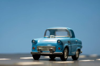 Asfalt yolda mavi bir oyuncak arabanın önü..