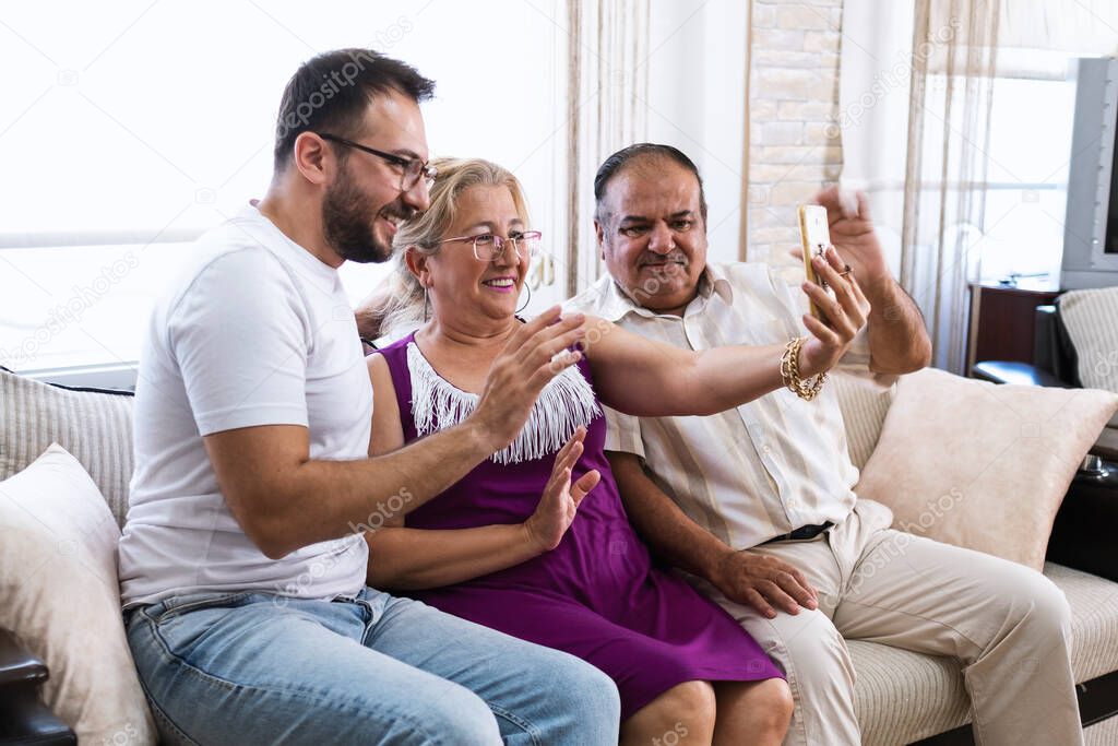 Turkish senior Husband, wife and their son with glasses are Celebrating Ramadan Festival of their relatives via video calling on a smartphone.