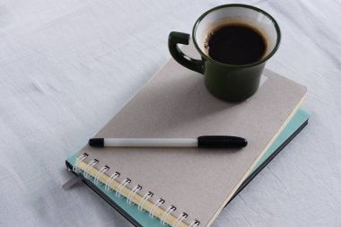 Not defterleri ve beyaz çarşafta bir fincan kahve.