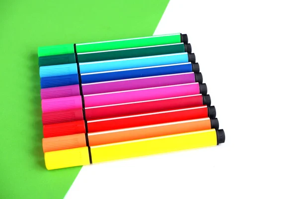 A set of colored markers in the form of a rainbow on a white-green background School supplies. suitable for advertising background.