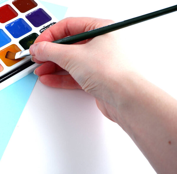 Beautiful watercolors with a brush on a blue and white background. Brush in hand