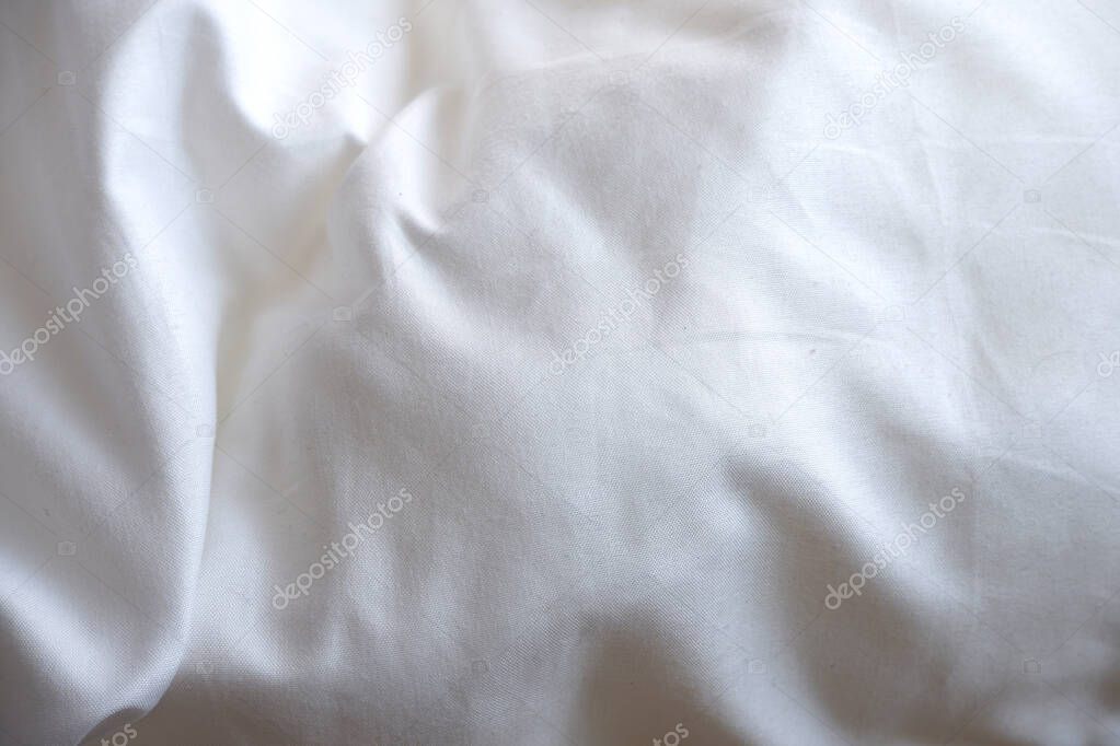 Soft white blanket. The sun's rays fall on the bed linen. Cosiness