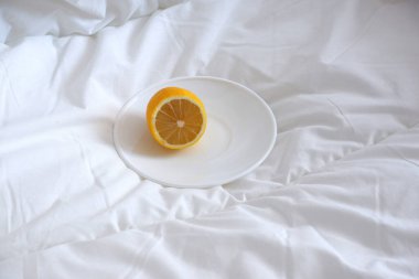 Tabakta limon, beyaz bir yatakta. Sıcaklık. Minimalizm.