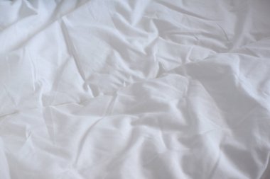 Yumuşak beyaz battaniye. Güneşin ışınları çarşafların üzerine düşer. Rahatlık