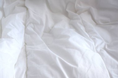 Yumuşak beyaz battaniye. Güneşin ışınları çarşafların üzerine düşer. Rahatlık