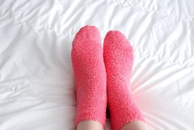 Yumuşak pembe çoraplarla, battaniyenin altından çıkan güzel pürüzsüz bacaklar..