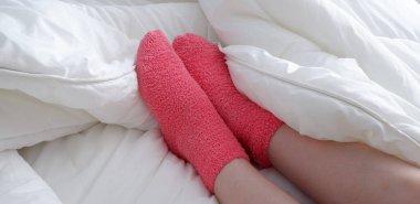 Yumuşak pembe çoraplarla, battaniyenin altından çıkan güzel pürüzsüz bacaklar..