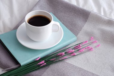 Yumuşak bir yatakta kahve ve çiçekler. İç mekan. Minimalizm. Sıcaklık. Güzel arkaplan