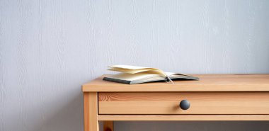 Şık ahşap bir masanın üzerinde bir kitap. Güzel iç mekan.