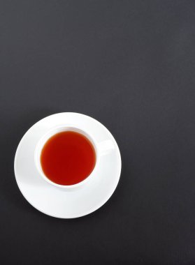 Siyah arka planda bir fincan çay. Set: beyaz seramik bardak ve fincan tabağı