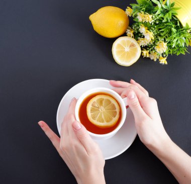 Bir fincan çay tutan eller. Siyah arka planda. Güzel tasarım arka planı. Kompozisyon.