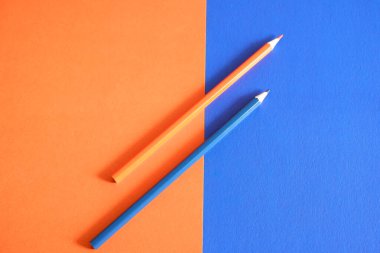 Orange and blue pencil on an orange-blue background clipart