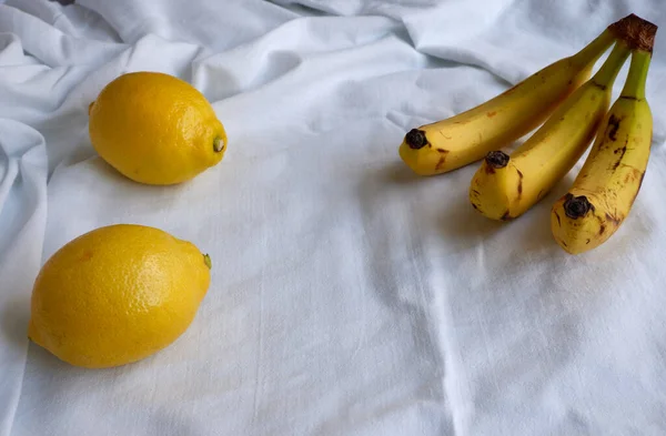 多汁的健康柠檬和成熟的香蕉放在白色的床上 漂亮的广告背景 — 图库照片