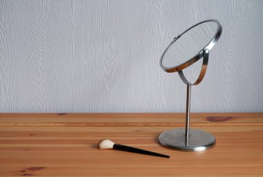 Ahşap bir masada ayna ve makyaj fırçası. Model ve reklam geçmişleri için uygun..