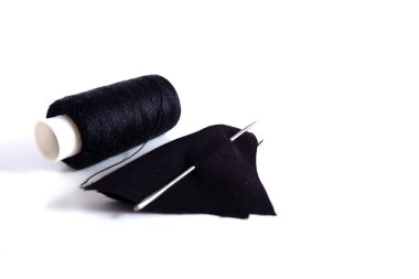 Dikiş aksesuarları: iğne ve kumaşlı siyah iplik. Beyaz arka planda. Reklam geçmişi için uygun