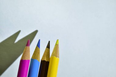 4 renkli kalem beyaz ofis duvarında 2 gölge bırakıyor.