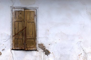 Penceresi beyaz duvarlı eski bir evin ahşap panjurlarıyla kapatılmış.