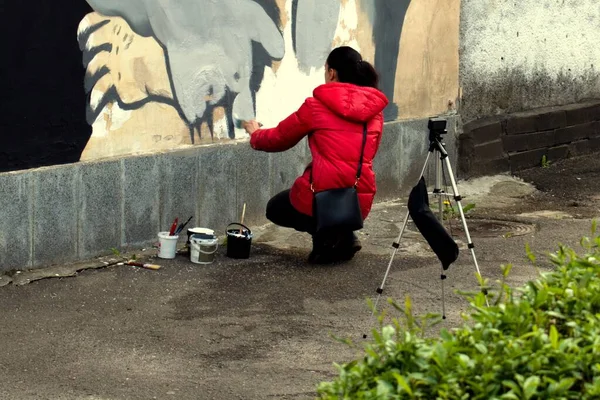 young woman with graffiti girl draws on the wall and makes video to the camera