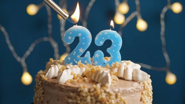 Bolo de aniversário com vela número 23 em backgraund azul incendiado por isqueiro. Close-up — Fotografia de Stock