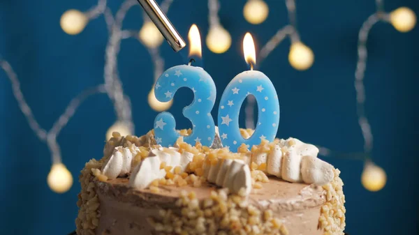 Bolo de aniversário com vela número 30 em backgraund azul incendiado por isqueiro. Close-up — Fotografia de Stock