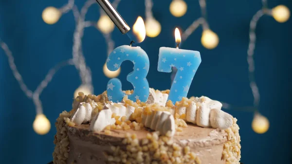 Tarta de cumpleaños con una vela de 37 números en el fondo azul incendiada por un encendedor. Primer plano —  Fotos de Stock