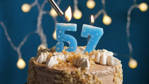 Pastel de cumpleaños con 57 número de vela en el fondo azul incendiado por el encendedor. Primer plano — Foto de Stock