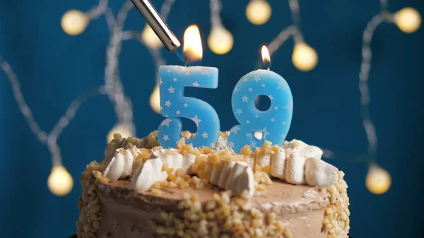 Birthday cake with 59 number candle on blue backgraund set on fire by lighter. Close-up — Stock Photo, Image