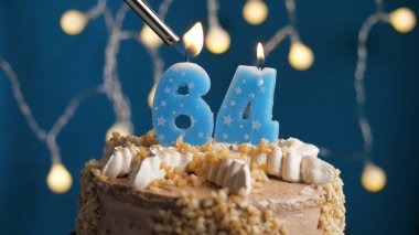 Doğumgünü pastası, üzerinde 64 numara mum olan mavi sırtı yanan bir mum. Yakın plan.