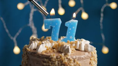 Doğum günü pastası, üzerinde 71 numara mum olan mavi sırtı yanan bir mum. Yakın plan.