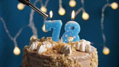 Doğum günü pastası, üzerinde 78 numara mum olan mavi sırtı yanan bir mum. Yakın plan.