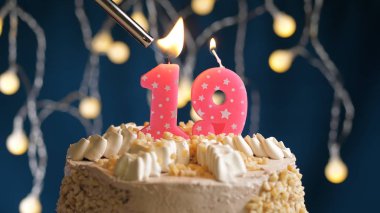 Yaş günü pastası. Mavi sırtta 19 numara mum var. Çakmak ateşine tutulmuş. Yakın çekim görünümü