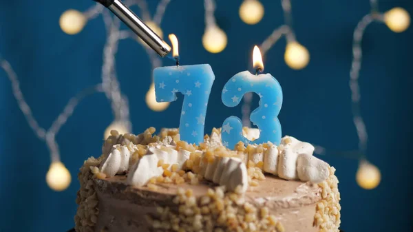 Pastel de cumpleaños con 73 número de vela en el fondo azul incendiado por el encendedor. Primer plano —  Fotos de Stock