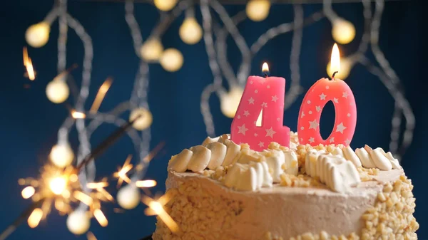 Birthday cake with 40 number pink candles and burning sparkler on blue backgraund. Close-up