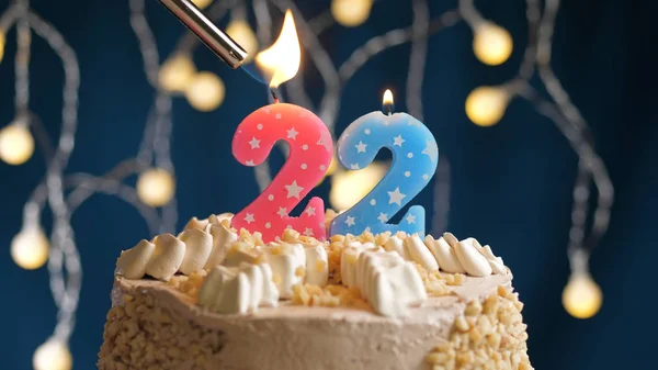 Bolo de aniversário com 22 vela número em backgraund azul incendiado por isqueiro. Vista de perto — Fotografia de Stock