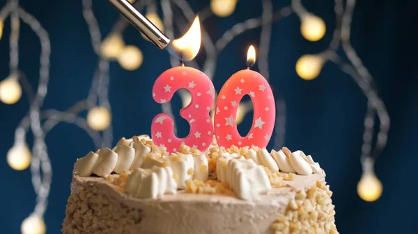 Verjaardagstaart met 30-cijferige kaars op blauwe achtergrond in brand gestoken door aansteker. Close-upzicht — Stockfoto