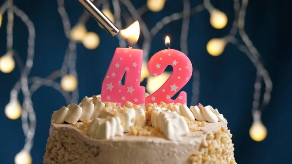 Bolo de aniversário com 42 vela número em backgraund azul incendiado por isqueiro. Vista de perto — Fotografia de Stock