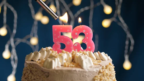 Verjaardagstaart met 53-cijferige kaars op blauwe achtergrond in brand gestoken door aansteker. Close-upzicht — Stockfoto