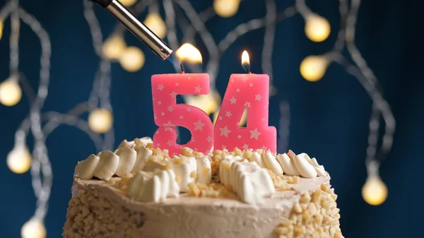 Verjaardagstaart met 54-cijferige kaars op blauwe achtergrond in brand gestoken door aansteker. Close-upzicht — Stockfoto