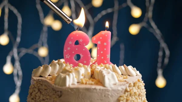 Pastel de cumpleaños con 61 número de vela en el fondo azul incendiado por el encendedor. Vista de primer plano —  Fotos de Stock