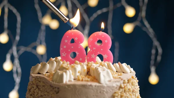 Gâteau d'anniversaire avec bougie numéro 68 sur fond bleu mis le feu par briquet. Vue rapprochée — Photo