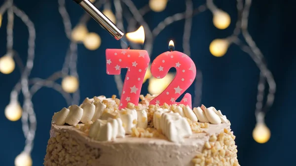 Tarta de cumpleaños con una vela de 72 números en el fondo azul incendiada por un encendedor. Vista de primer plano —  Fotos de Stock