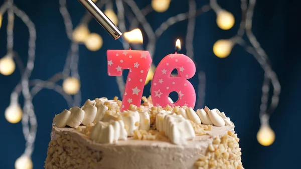 Pastel de cumpleaños con 76 número de vela en el fondo azul incendiado por el encendedor. Vista de primer plano —  Fotos de Stock
