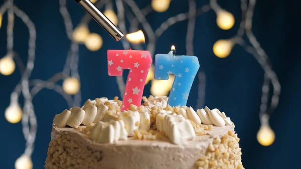 Születésnapi torta 77 számjegyű gyertyával a kék hátán, öngyújtóval felgyújtva. Közelkép — Stock Fotó
