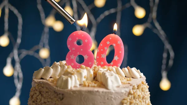 Birthday cake with 80 number candle on blue backgraund set on fire by lighter. Close-up view — Stock Photo, Image