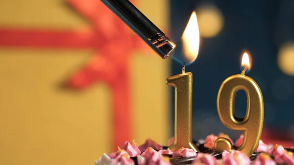 Birthday cake number 19 golden candles burning by lighter, background gift yellow box tied up with red ribbon. Close-up — Stok fotoğraf