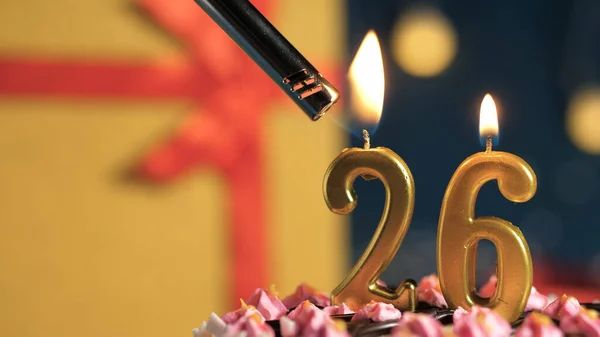 Tort de ziua de naștere numărul 26 lumânări de aur care ard de brichetă, cadou de fundal cutie galbenă legată cu panglică roșie. Close-up — Fotografie, imagine de stoc