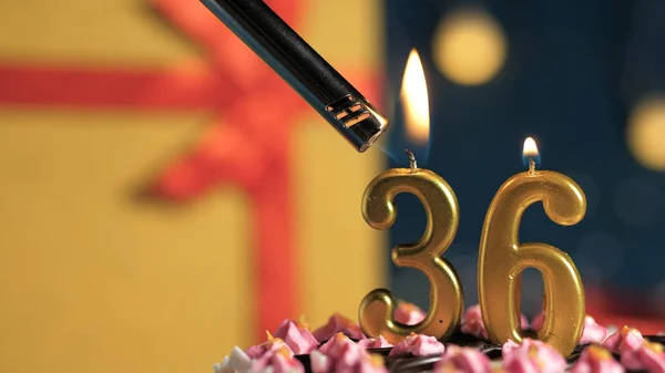 Tort de ziua de naștere numărul 36 lumânări de aur care ard de brichetă, cadou de fundal cutie galbenă legată cu panglică roșie. Close-up — Fotografie, imagine de stoc
