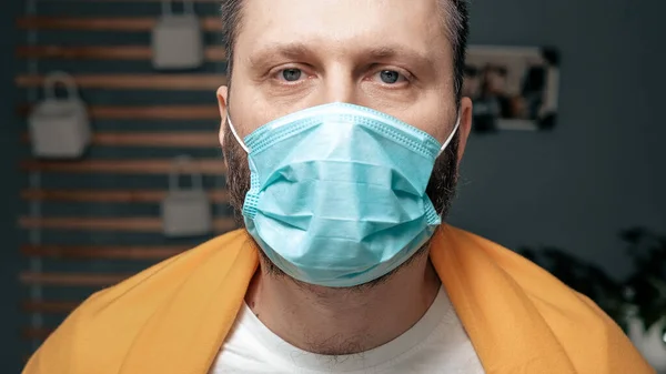 Man in respiratory mask. Masked attractive guy looks at camera. Cold, flu, virus, tonsillitis, acute respiratory disease, quarantine, epidemic concept. Close-up