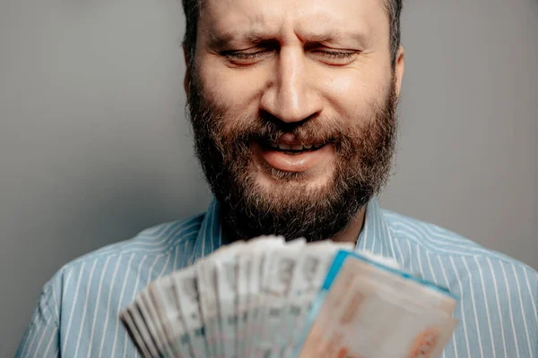 Russian ruble falling going down inflation concept. Portrait of man looks at bundle of money rubles and expresses emotions of frustration, pain, hopelessness. Close-up view